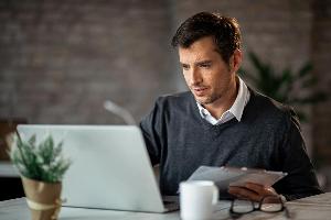 mid-adult-businessman-entering-data-from-business-reports-in-a-computer-at-the-office.jpg